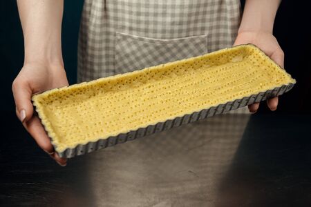 Woman hold pierced dough for blind baking. Woman's hands making cookie pastry for tart.の写真素材