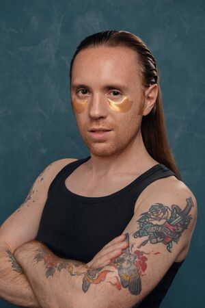 Portrait of a man with tattoos and long hair with patches under his eyes.の写真素材