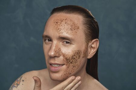 Man with wet long hair in coffee mask on his face waiting of the spa proceduresの写真素材