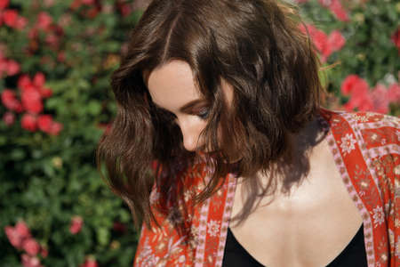 Young beautiful sexy woman posing in front of rose bush. Outdoor fashion portrait of a romantic girl with hard light.の写真素材