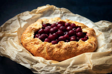Galette with ripe red cherry filling on white wooden background. Homemade sweet open pie on Provence style background. Top view.の写真素材