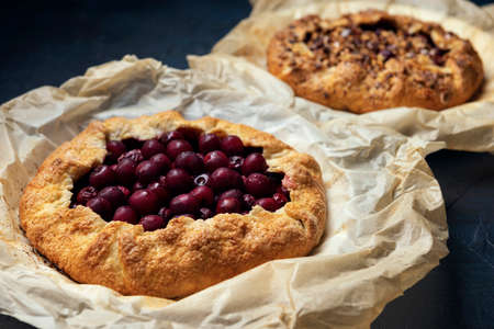Galette with ripe red cherry filling on white wooden background. Homemade sweet open pie on Provence style background. Top view.の写真素材