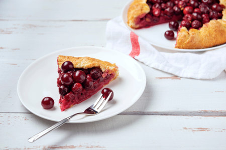 Two galettes with ripe red cherry and walnut filling on dark blue background. Homemade sweet open...