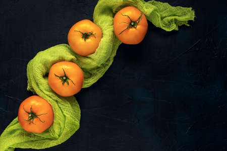 Red wet cherry tomatoes and yellow tomato fruits in black plate on a dark textured background. Top view. Flat lay. Space for text.の写真素材
