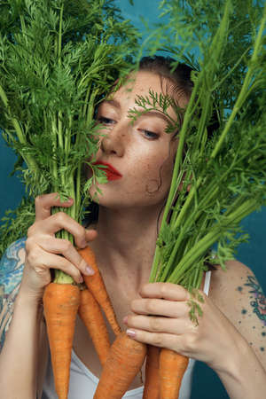 Portrait of dreaming female fashion model hiding behind carrot leaves.の写真素材