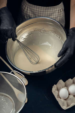 Women in checkered apron mixing wheat flour, milk and yeast with wire whisk. Process of making bakery. The Adjarian Khachapuri Recipe â Georgian cheese bread.の写真素材
