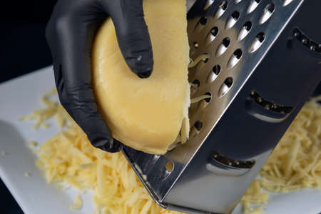 Hands in black gloves rub cheese on a grater. Home cooking. The Adjarian Khachapuri Recipe â Georgian cheese bread.の写真素材