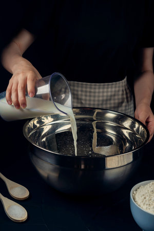 Woman in checkered apron pours milk into a bowl. Process of making bakery. Adjarian Khachapuri...