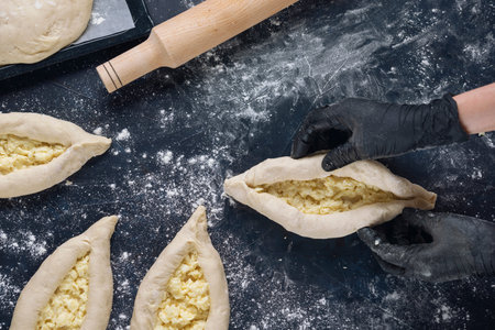 Woman in black gloves holds raw khachapuri. Process of making bakery. The Adjarian Khachapuri Recipe...