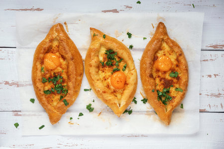 Adjarian Khachapuri â€“ Georgian cheese bread. Three baked open pies with cheese and egg yolk...