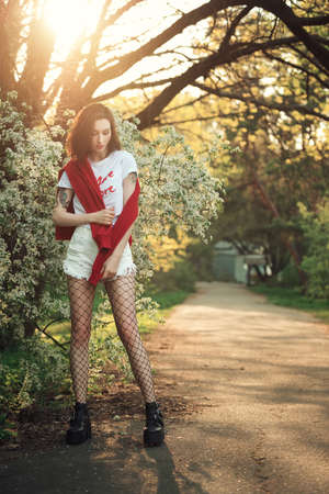 Young dreamed woman with white blooming bush. Pretty fashion girl near the white flowers.の写真素材