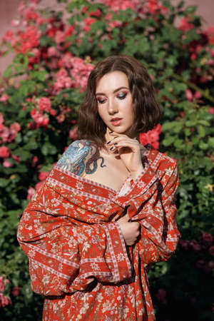 Young pretty female fashion model posing in front of the rose bush. Cityscape portrait.の写真素材