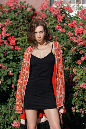 Young pretty fashion model looks directly in the camera and posing in front of the rose bush.の写真素材