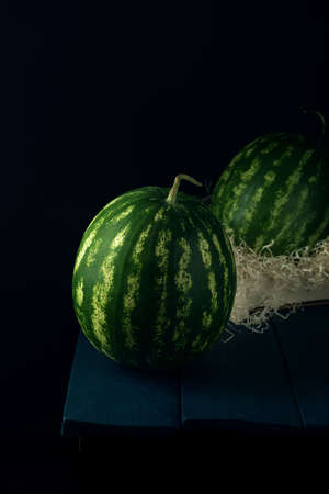 Two green ripe watermelons on dark blue wooden table.の写真素材