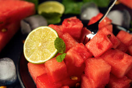 Close-up watermelon cubes, mint, lime and ice cubes on the black textured backdrop.の写真素材