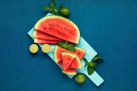 Watermelon slices, mint and lime on the blue wooden background. Top view. Flat lay.の写真素材
