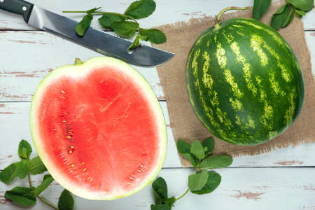 One whole watermelon with sliced one and knife on the white wooden Provence style background. Flat lay.の写真素材