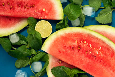 Close-up, watermelon slices, mint and lime on the blue wooden background. Top view. Flat lay.の写真素材