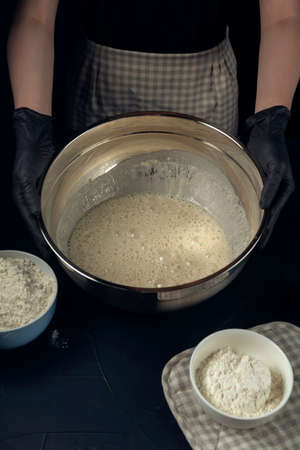 Woman in checkered apron hold bowl with liquid yeast dough. Process of making bakery. The Adjarian Khachapuri Recipe â Georgian cheese bread.の写真素材