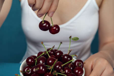 Close-up cherries in front of the female in the white shirt.の写真素材