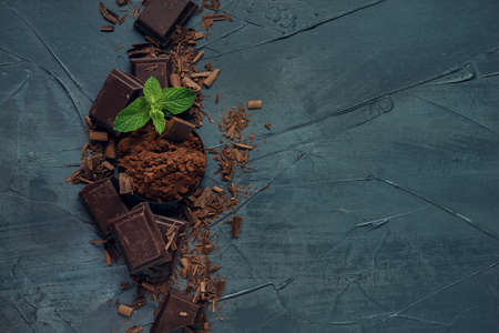 Bowl with cocoa powder, pieces of chocolate, chocolate shavings and mint on the grey textured background. Top view. Flat lay. Copy space.の写真素材