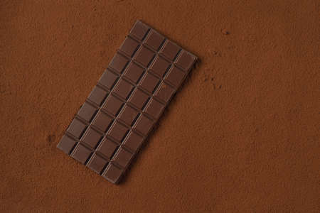Chocolate bar on the table covered with cocoa powderの写真素材