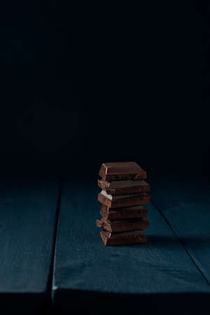 Heap of chocolate pieces on dark blue wooden table. Copy space. Space for text.の写真素材