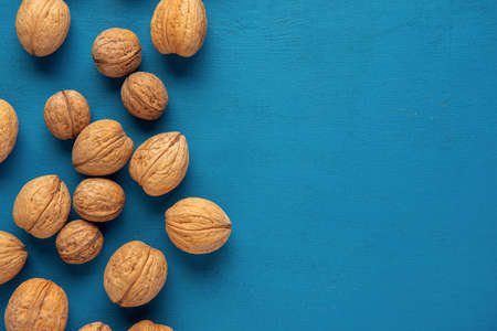 Scattered walnuts on the blue background. Flat lay. Copy space.の写真素材