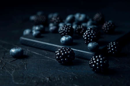 Scattered blueberry and blackberry on the dark textured background.の写真素材
