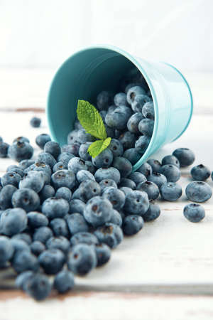 Turned bucket with blueberry and mint leaves on the white Provence style wooden table.の写真素材