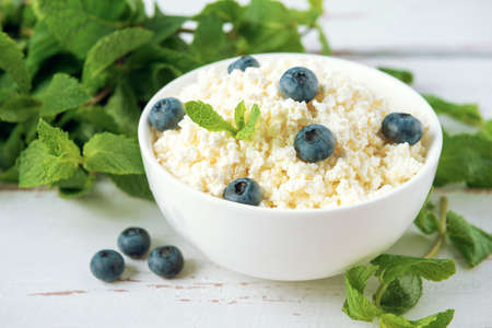 Cottage cheese with blueberries and mint leaves on the  white Provence style wooden tableの写真素材