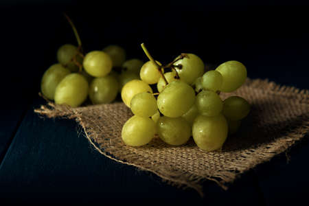 Close-up part of grape cluster on the burlap napkin and the dark wooden table.の写真素材