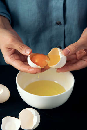 Woman breaks egg into the bowl. Cooking process. Bakery making. Cottage cheese casserole making.の写真素材