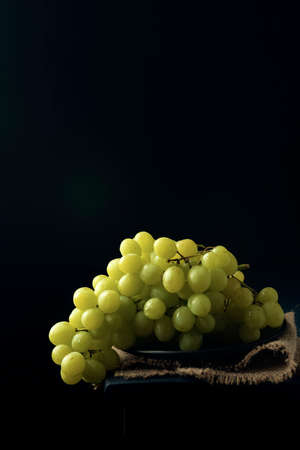 Grape cluster on the burlap napkin on the edge of dark wooden table.の写真素材