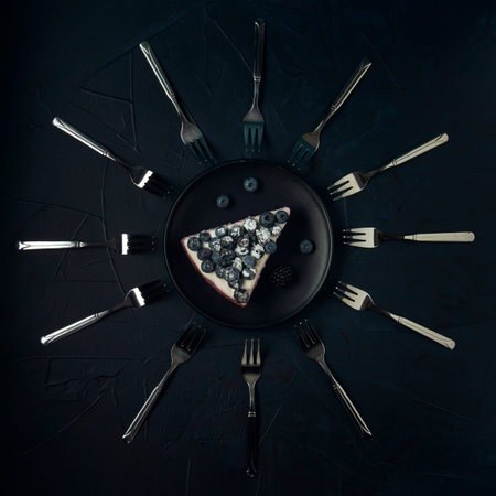 A piece of cottage cheese casserole and twelve dessert forks on the dark textured background.