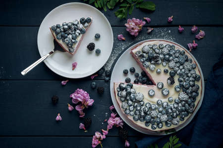 Piece of cottage cheese casserole with cake server. Cheese pie decorated with blackberry, blueberry and mint leaves on the dark wooden table. Flat lay.の写真素材