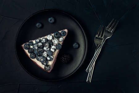 Black plate with a piece of cottage cheese casserole and cutlery on the dark textured background. Flat lay.の写真素材
