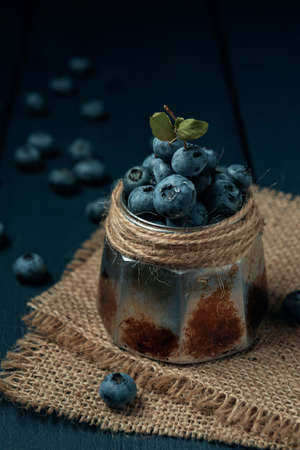 Metal bowl with wet ripe blueberry on burlap napkin and the dark wooden table.の写真素材