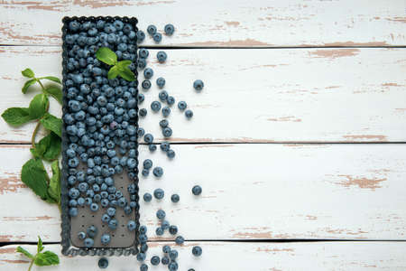 Box with blueberry and mint leaves on the white Provence style wooden table. Flat lay. Copy space.の写真素材
