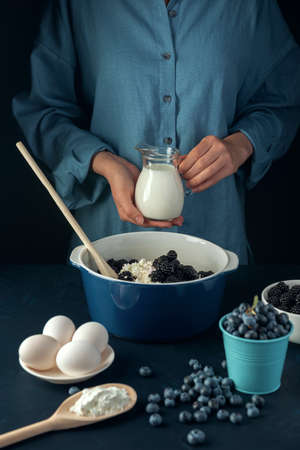 Woman holds glass jug with cream. Cooking process. Cottage cheese casserole making.の素材 [FY310154473207]