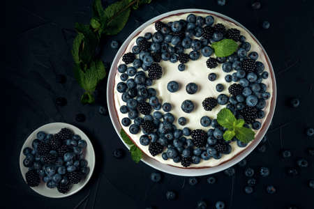 Plate with blackberry and blueberry, cottage cheese casserole on the dark textured background. Flat lay.の写真素材