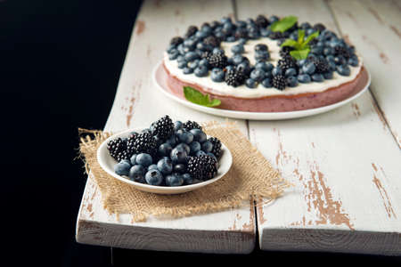White plate with blackberry and blueberry on the burlap napkin and cottage cheese casserole on the background.の写真素材
