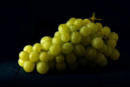 Grape cluster on the dark blue wooden table. Fruit on the dark background.の写真素材