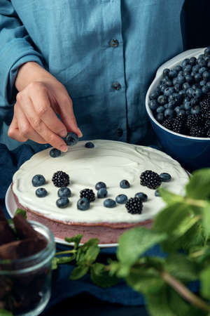Woman hand put blueberry on the cottage cheese casserole. Decoration process cottage cheese pie with berries.の写真素材
