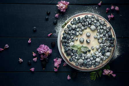Cottage cheese casserole with blackberry and blueberry sprinkled with icing sugar and decorated with the acacia flowers. Flat lay. Copy space.の写真素材