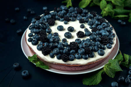 Cottage cheese casserole decorated with blackberry, blueberry and mint leaves on the dark textured background.の写真素材
