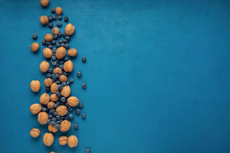 Scattered walnuts and blueberry on the blue background. Flat lay. Copy space.の写真素材