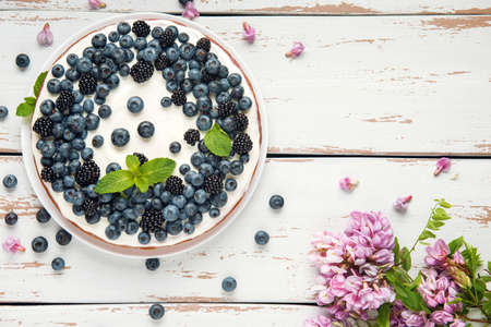 Cottage cheese casserole with blackberry and blueberry on white Provence style table. Sweet pie with acacia flowers and mint leaves. Flat lay. Copy space.の写真素材