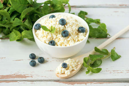 Cottage cheese with blueberries and mint leaves on the white Provence style wooden tableの写真素材