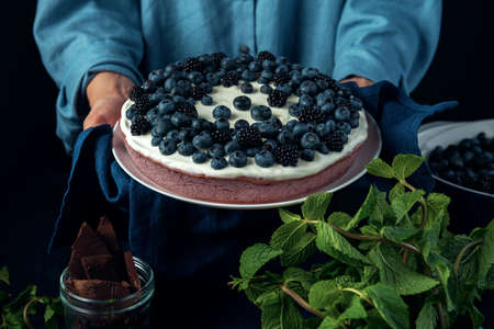 Female hands hold cottage cheese pie decorated with blackberry and blueberry.の写真素材